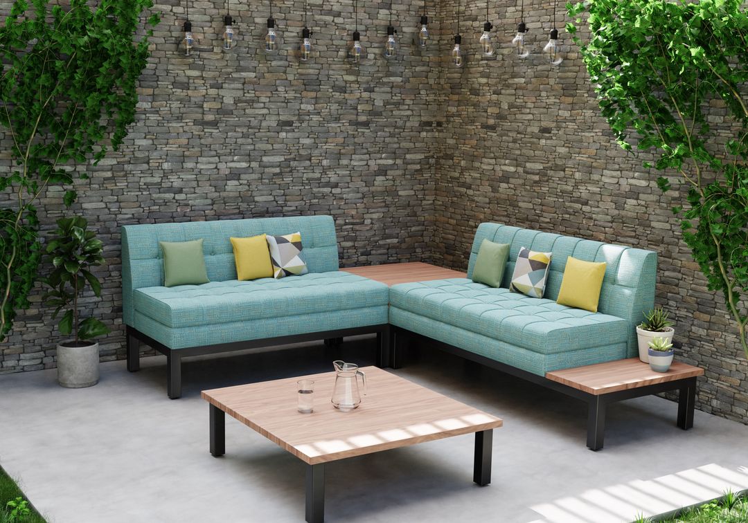 Teal L-shaped outdoor sofa and wood coffee table against a brick wall